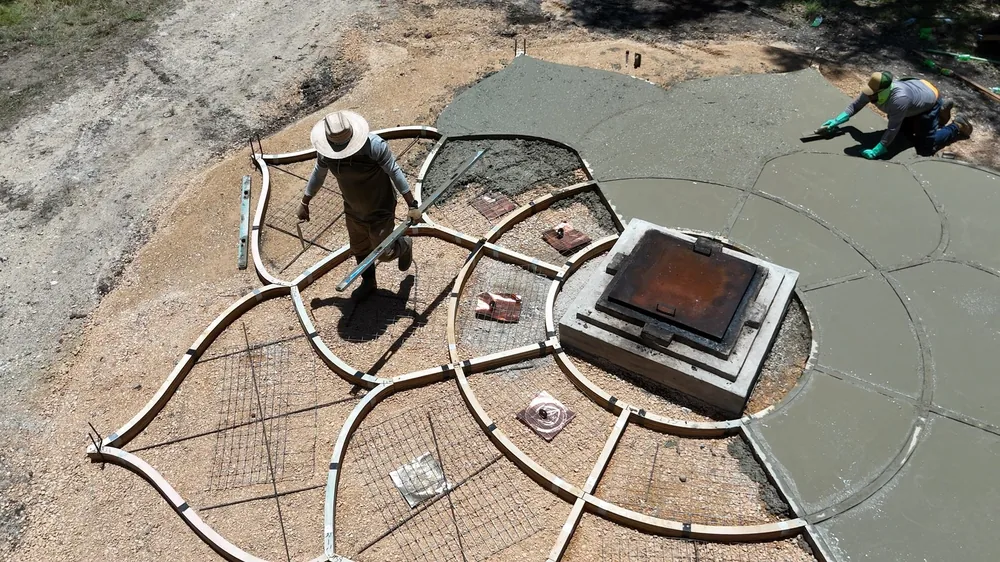 Pour day at the Lotus: the birch forms on the ground, one man crossing them with a screed, another finishing a petal, the square base cast at the centre.