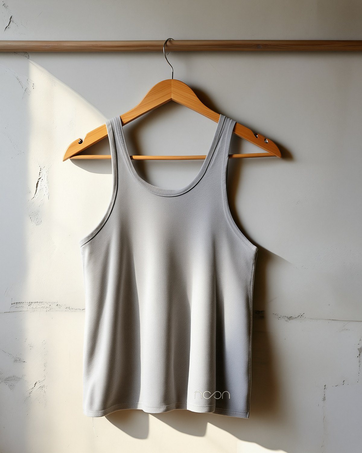 A thin grey tank on a hanger, the word noon small at the hem