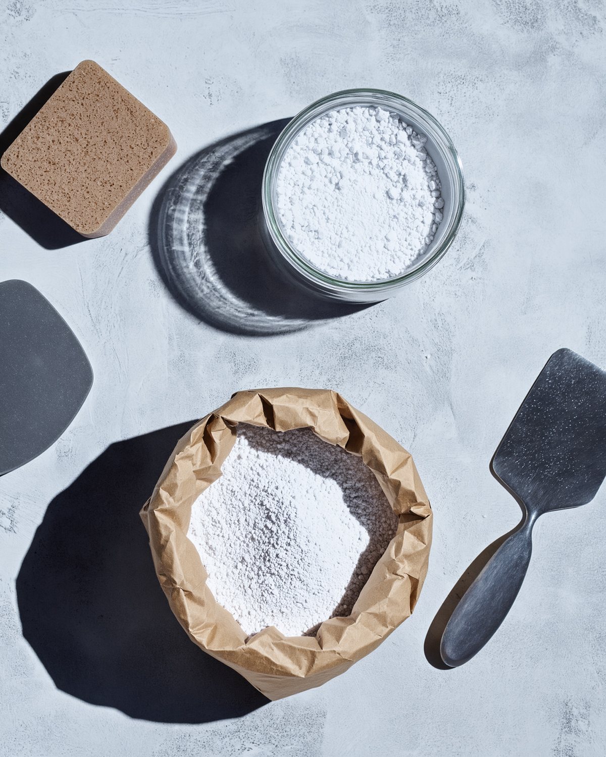 Lime, marble dust, black soap, a polishing stone and a trowel laid out on concrete