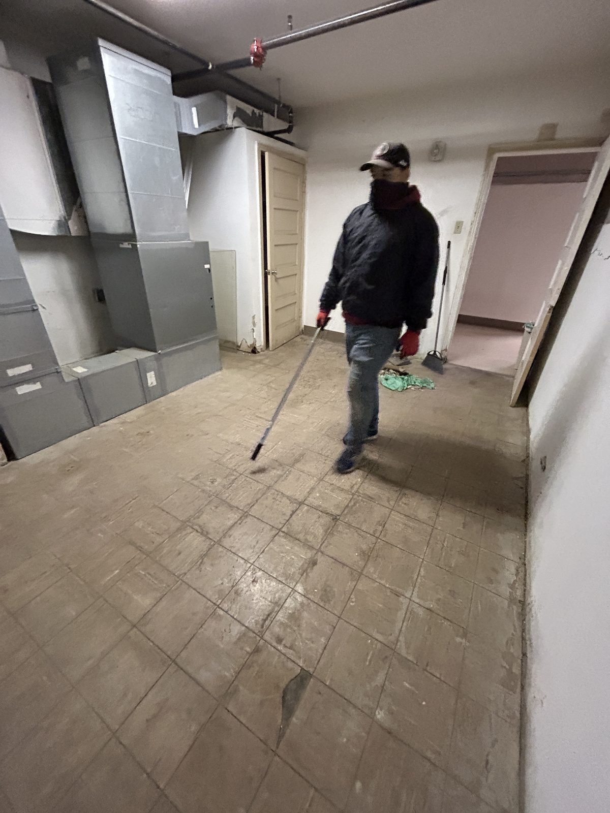 A crew member sweeping the grimy tile floor clear by hand, gloved and scarfed against the dust.