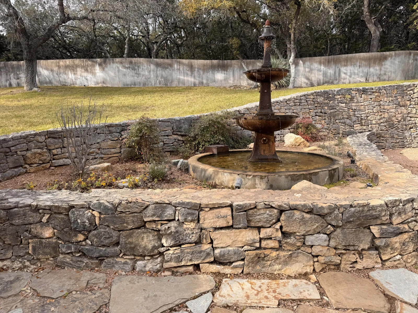 The garden's tiered stone fountain, ringed by dry-stacked limestone and planted beds in flower.