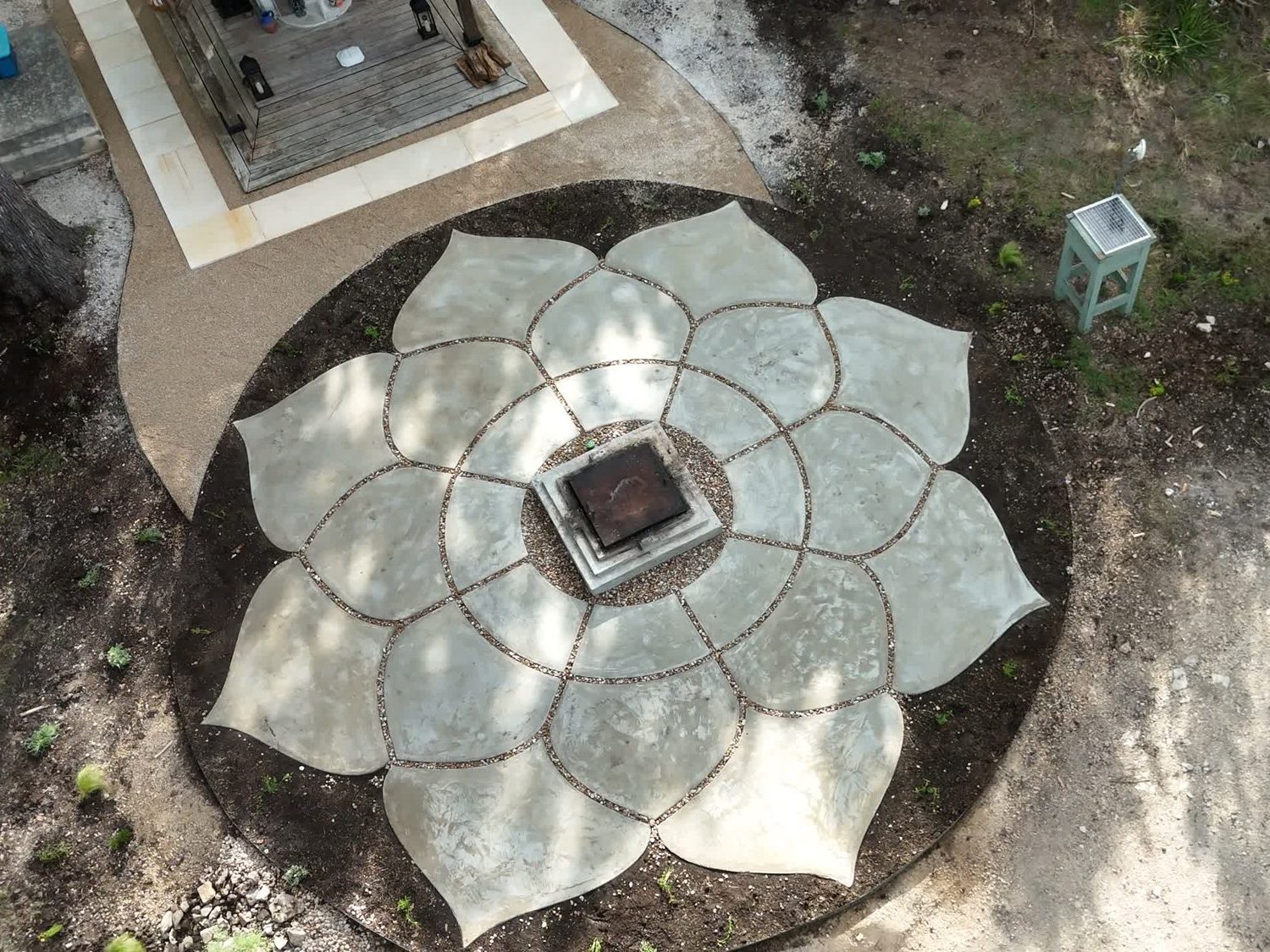 The finished Lotus seen straight down from a drone: eight concrete petals around the square shrine base, pebble joints between them, the shrine deck beyond.
