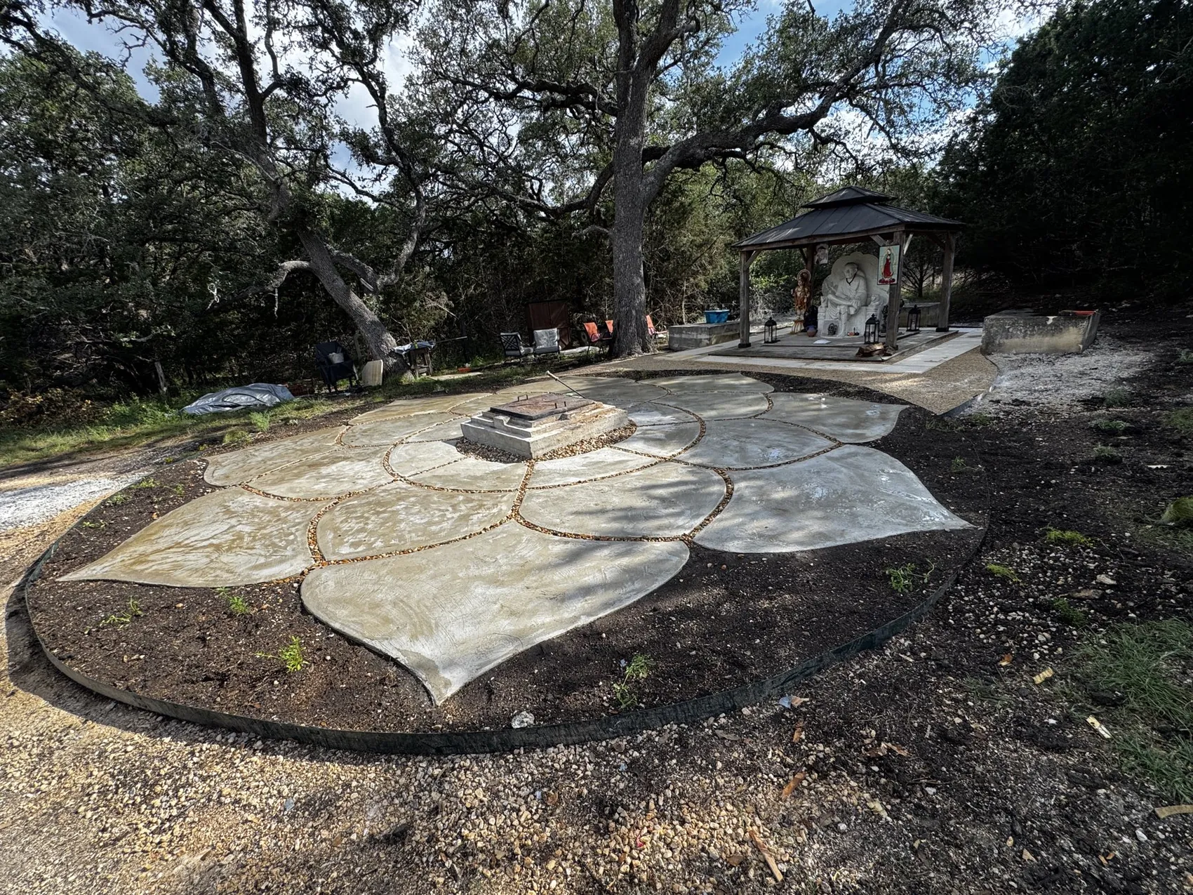 The finished 28-foot cast-concrete Lotus among live oaks, its stone petals laid out beneath the canopy