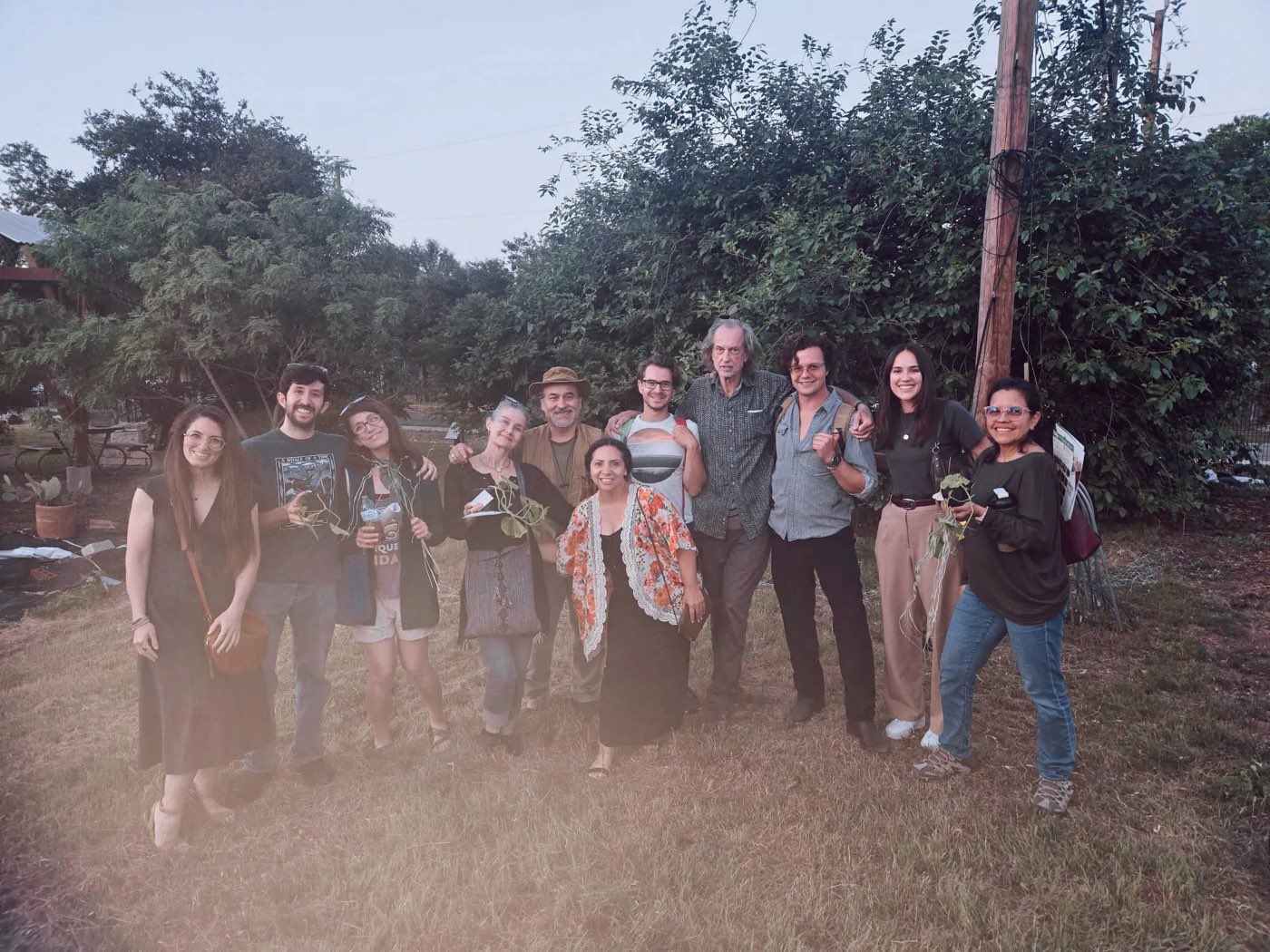 The Noon community gathered at dusk in a Hill Country garden, holding native plant starts and cuttings.