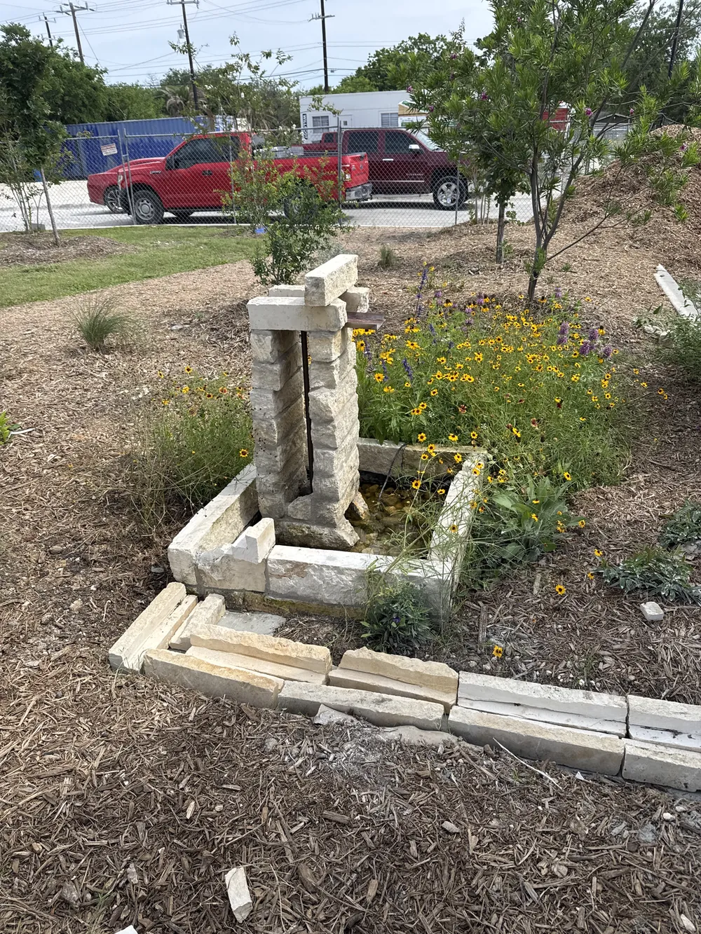 The cast fountain at the head of the rill, blanketflowers around it.