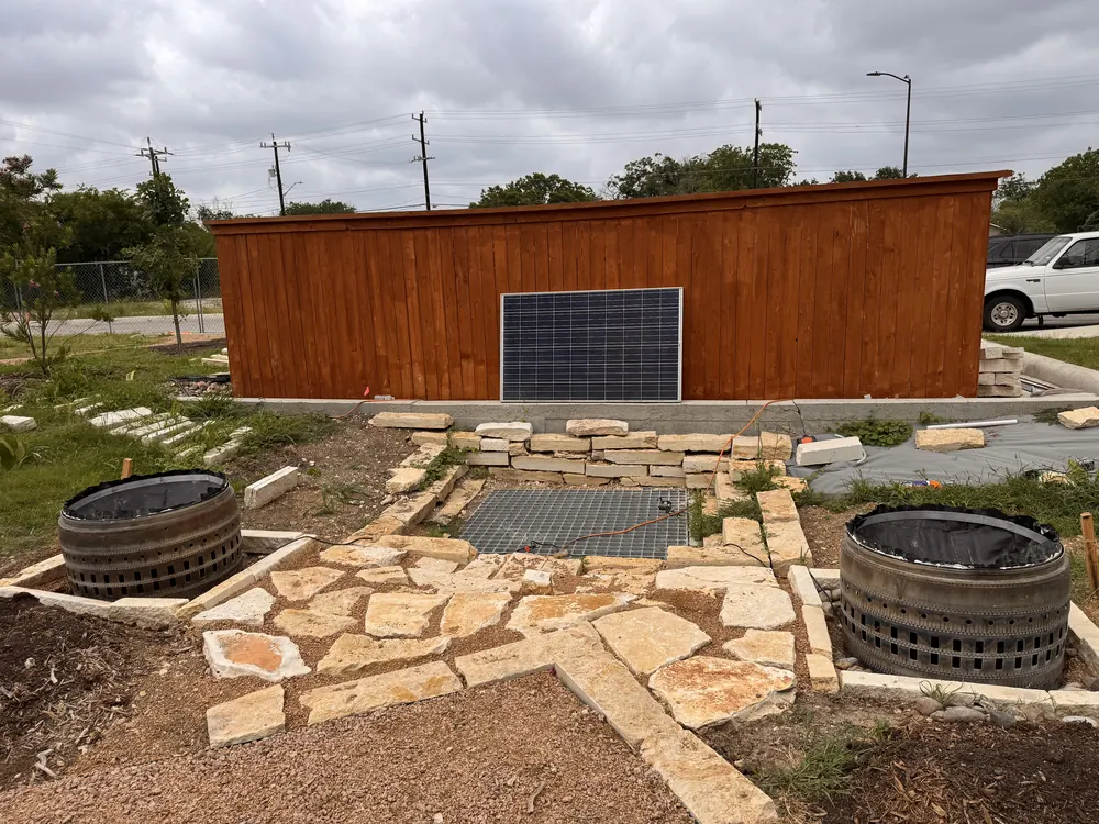 A solar panel on a cedar wall above two cast basins.