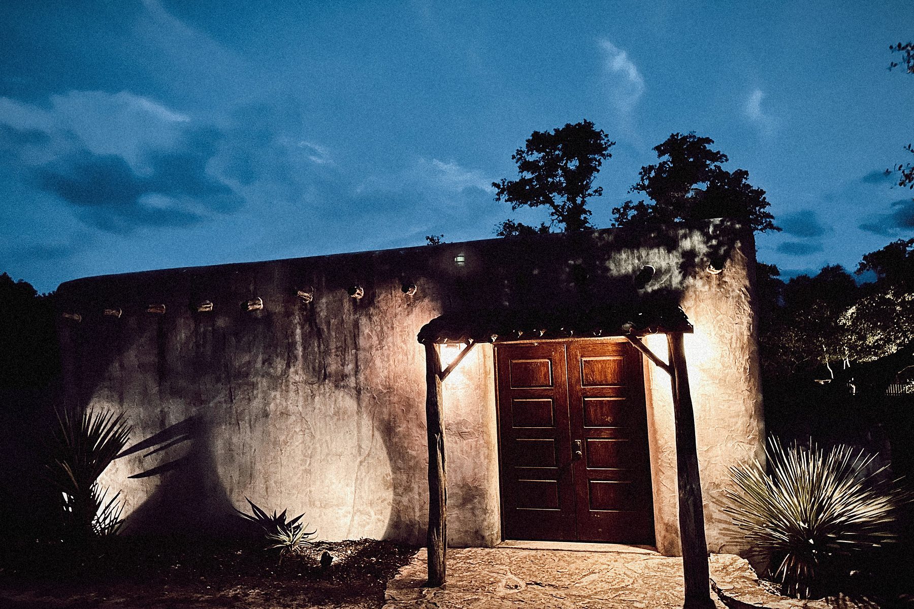 The courtyard gate at dusk, yuccas either side, the lanterns lit.