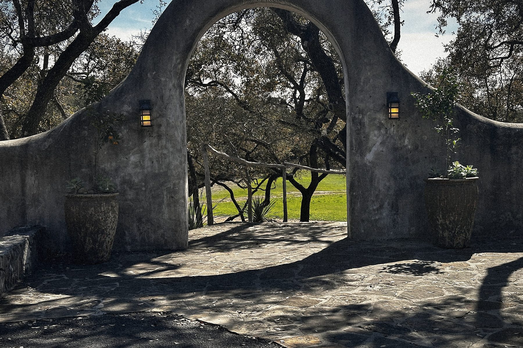 The arch to the grounds, live oaks beyond.