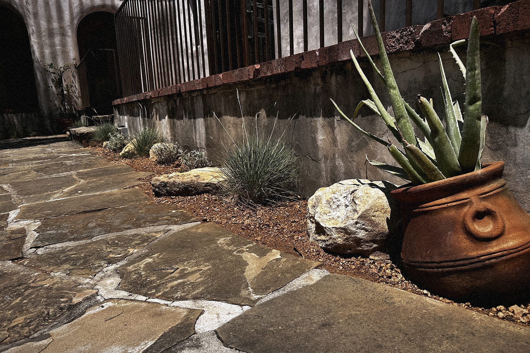 A clay pot on the flagstone, the stone-edged bed behind.