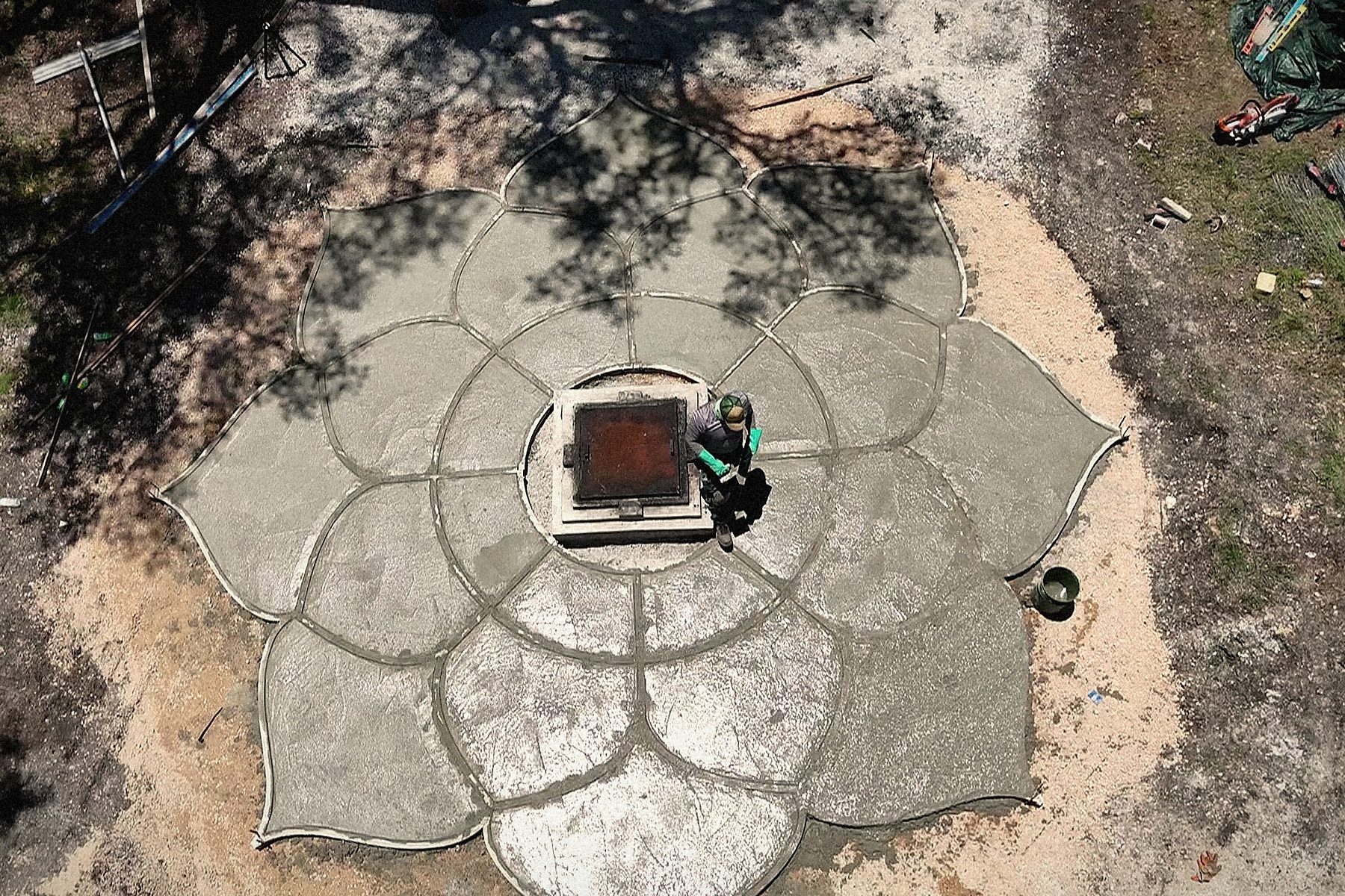 Pour day from above: the eight petals placed and screeded, the surface still wet, the finisher at the plinth.